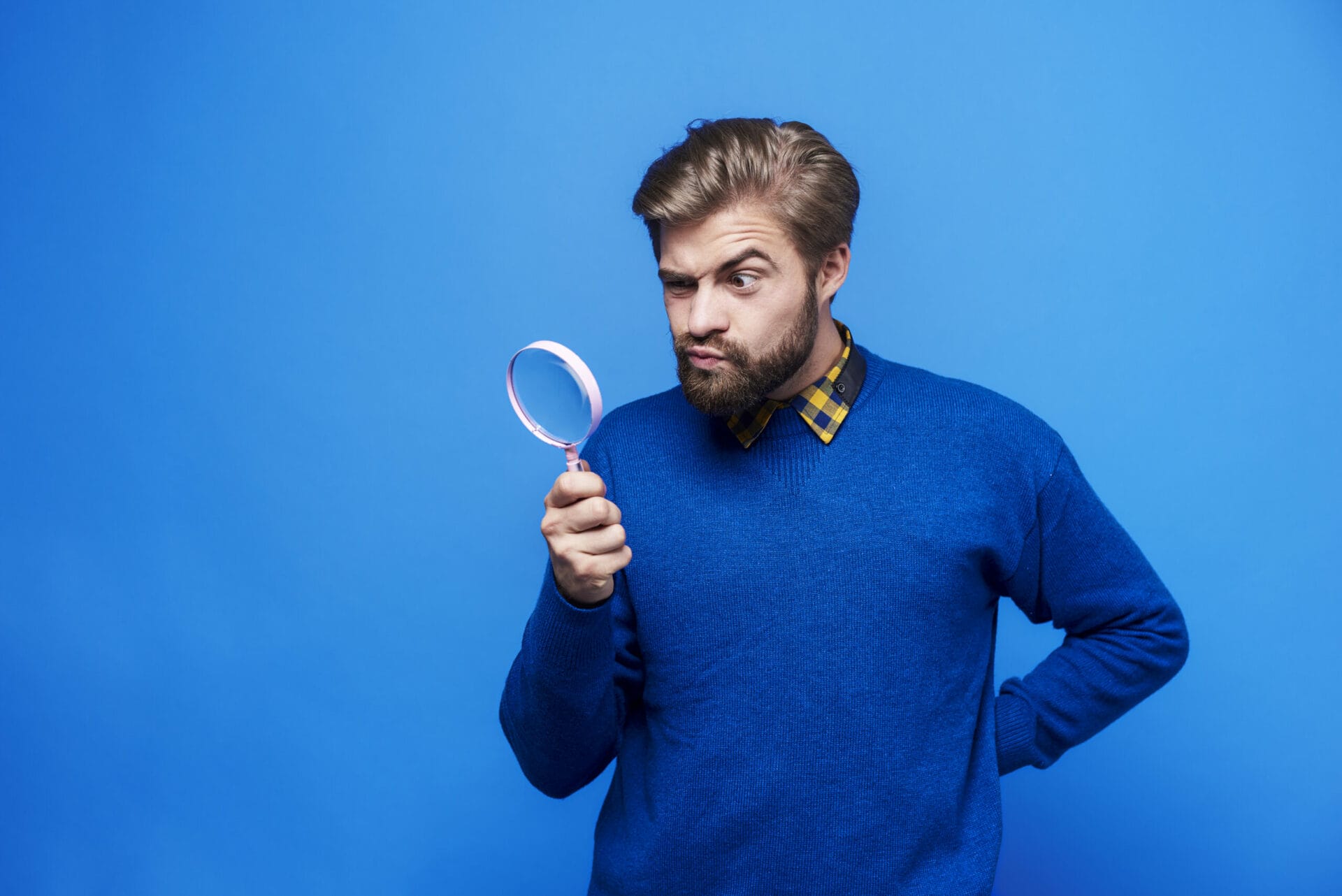 Un homme avec une loupe examine attentivement quelque chose, symbolisant la quête spirituelle et la recherche de Jésus.