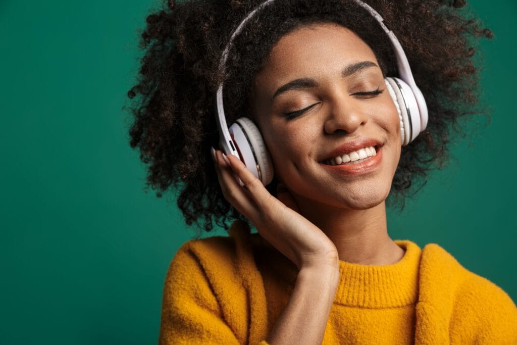 Femme souriante avec un casque audio, représentant l’écoute spirituelle et la connexion avec Dieu.